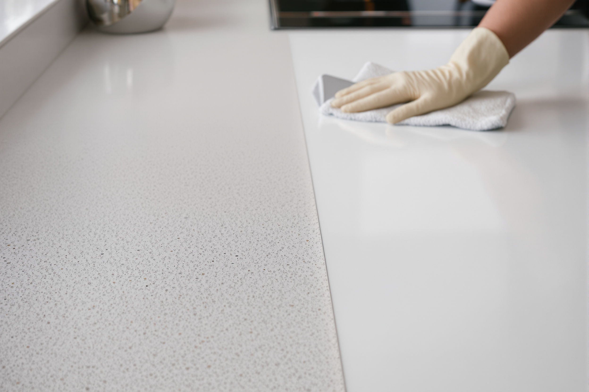 Half-cleaned quartz worktop showing plaster dust on one side and the clean surface on the other during a builders clean